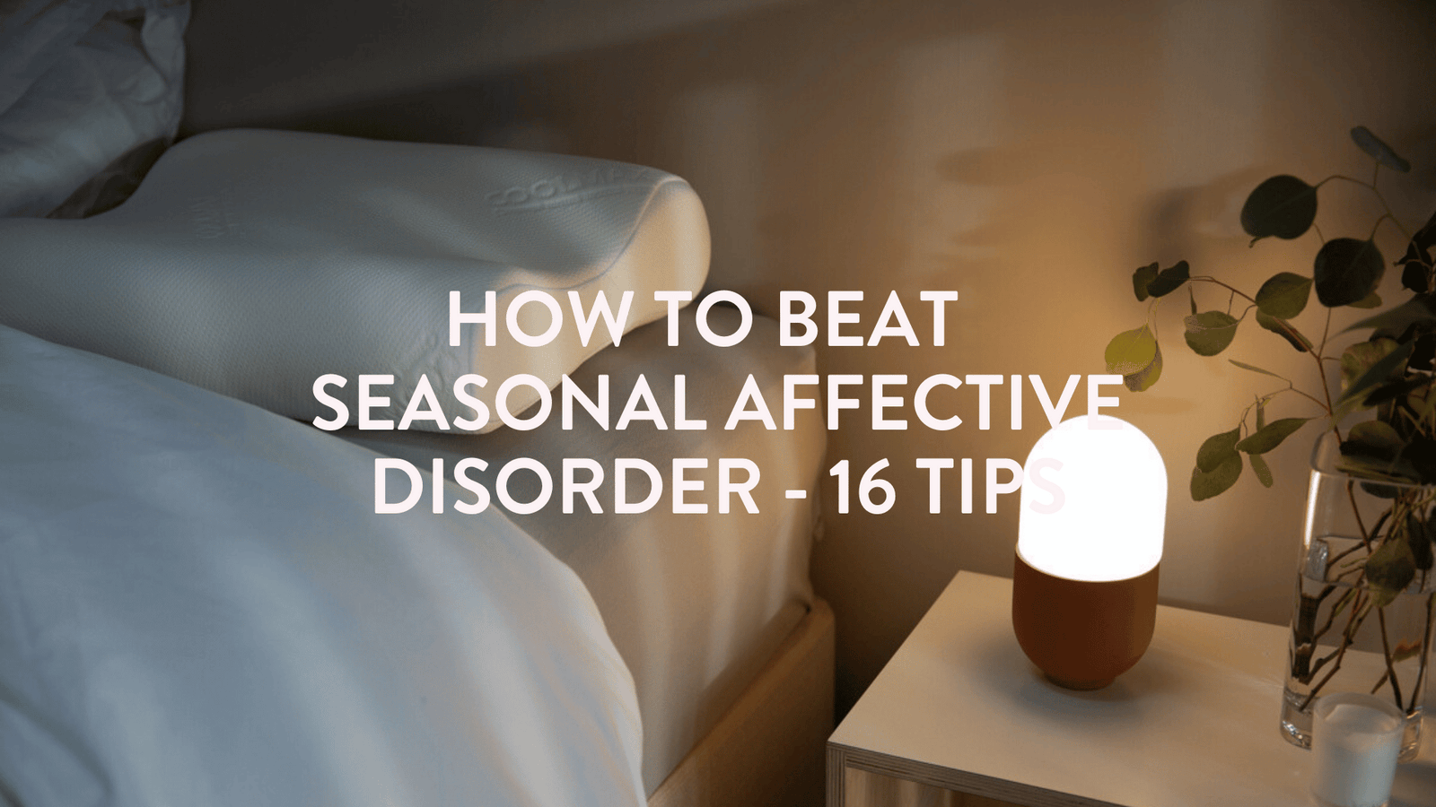 a quiet scene of a bed, pillow and seasonal affective disorder SAD lamp on the bedside table 