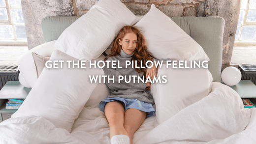 person sitting in bed surrounded by white pillows