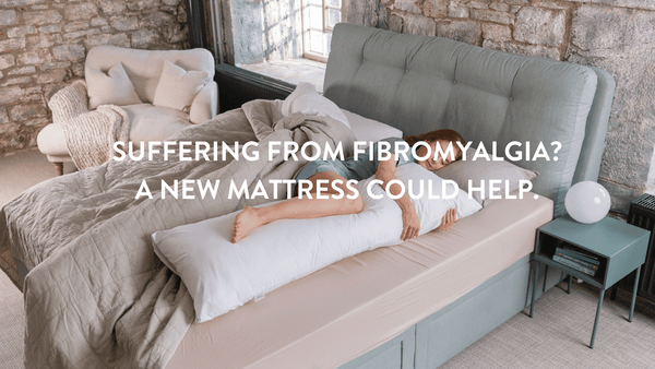 Person lying on a bed hugging a Putnams fibromyalgia pillow  